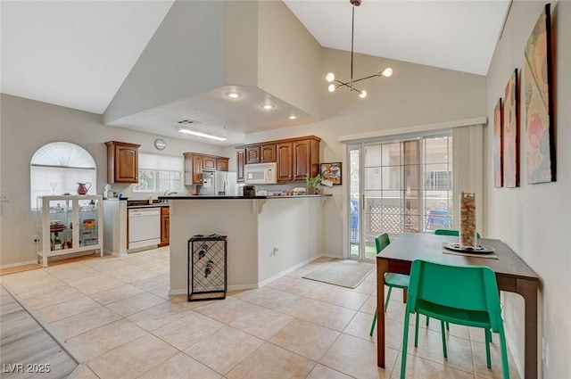 2925 Wigwam Pkwy Unit 123, Henderson, NV 89074 - kitchen featuring white appliances, a peninsula, dark countertops, a chandelier, and hanging light fixtures