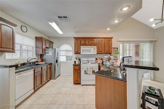 2925 Wigwam Pkwy Unit 123, Henderson, NV 89074 - kitchen with white appliances, plenty of natural light, dark stone counters, light tile patterned floors, and vaulted ceiling