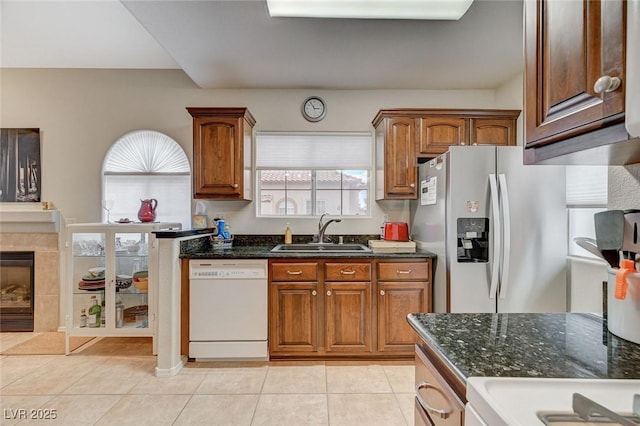 2925 Wigwam Pkwy Unit 123, Henderson, NV 89074 - kitchen featuring dishwasher, light tile patterned flooring, stainless steel fridge, dark stone countertops, and brown cabinetry