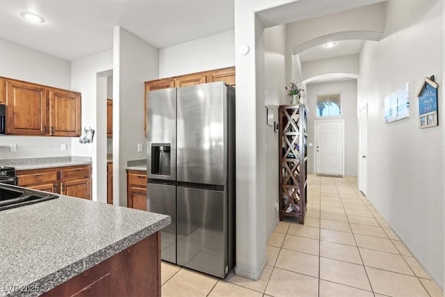 4916 White Jade St, North Las Vegas, NV 89081 - kitchen featuring stainless steel fridge with ice dispenser, arched walkways, light tile patterned floors, and brown cabinets