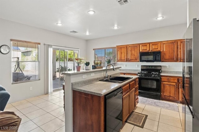 4916 White Jade St, North Las Vegas, NV 89081 - kitchen featuring black appliances, light tile patterned flooring, brown cabinets, an island with sink, and recessed lighting