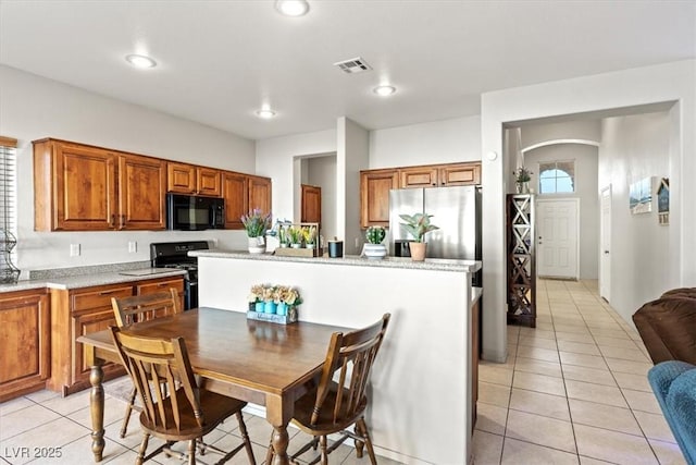 4916 White Jade St, North Las Vegas, NV 89081 - kitchen with black appliances, light tile patterned floors, brown cabinets, arched walkways, and recessed lighting