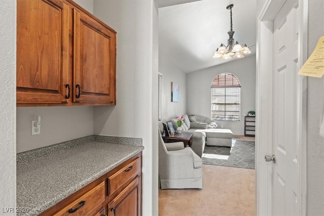4916 White Jade St, North Las Vegas, NV 89081 - kitchen with a chandelier, brown cabinets, lofted ceiling, pendant lighting, and open floor plan