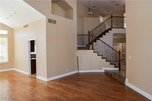 2208 Fiero Dr, Las Vegas, NV 89134 - unfurnished living room with high vaulted ceiling, stairway, and wood finished floors