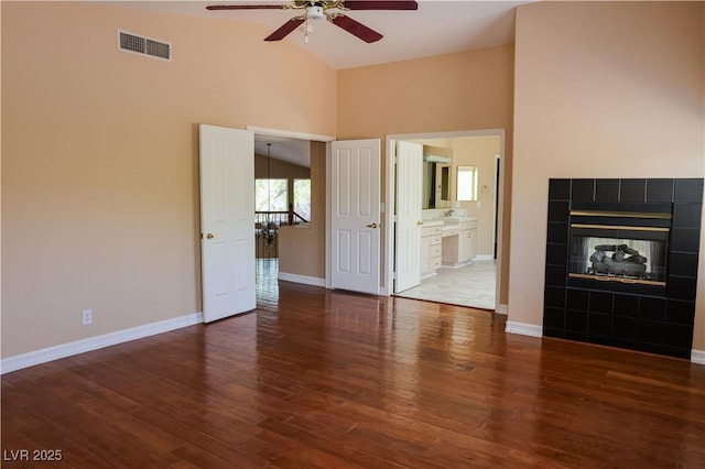 2208 Fiero Dr, Las Vegas, NV 89134 - unfurnished living room featuring ceiling fan, high vaulted ceiling, wood finished floors, and a tile fireplace