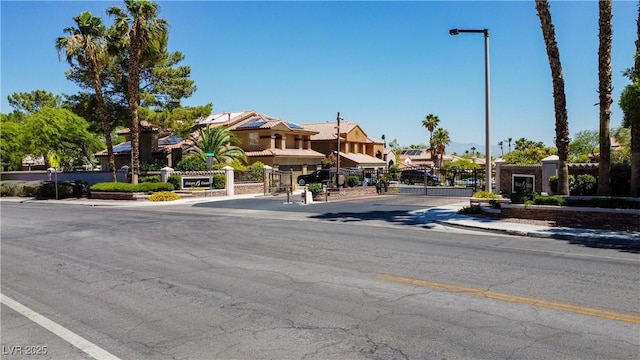 2208 Fiero Dr, Las Vegas, NV 89134 - view of asphalt road featuring a gate, sidewalks, street lighting, a residential view, and curbs