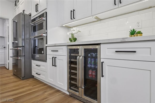 9900 Summer Ash Ct Unit 103, Las Vegas, NV 89134 - kitchen featuring beverage cooler, appliances with stainless steel finishes, white cabinets, and light wood-type flooring