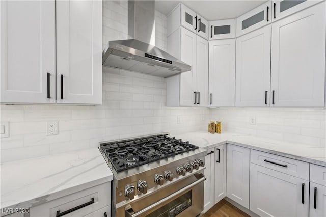 9900 Summer Ash Ct Unit 103, Las Vegas, NV 89134 - kitchen with wall chimney exhaust hood, high end stove, tasteful backsplash, and white cabinetry