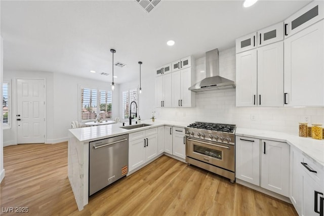 9900 Summer Ash Ct Unit 103, Las Vegas, NV 89134 - kitchen featuring appliances with stainless steel finishes, wall chimney exhaust hood, a peninsula, light wood-type flooring, and recessed lighting