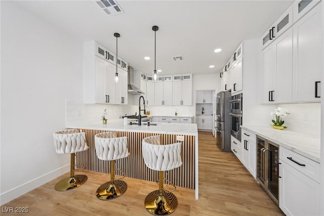 9900 Summer Ash Ct Unit 103, Las Vegas, NV 89134 - kitchen with wall chimney range hood, a peninsula, light wood finished floors, a kitchen breakfast bar, and recessed lighting