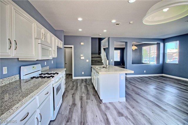 6042 Thorne Bay Ct, Las Vegas, NV 89110 - kitchen with white appliances, white cabinets, light wood finished floors, recessed lighting, and light stone counters