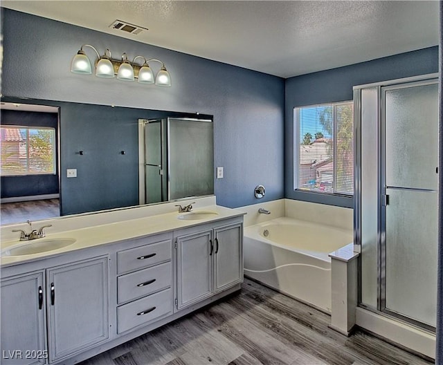 6042 Thorne Bay Ct, Las Vegas, NV 89110 - full bathroom with wood finished floors, plenty of natural light, double vanity, a garden tub, and a textured ceiling