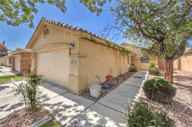 5687 Harbour Pointe Ave, Las Vegas, NV 89122 - view of side of home with stucco siding, an attached garage, a tile roof, and driveway
