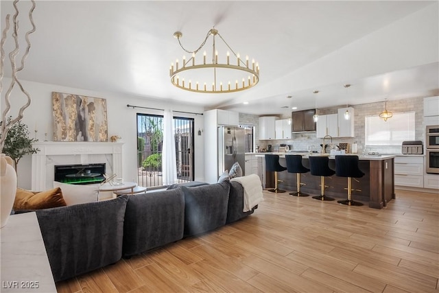 4774 Walteta Way, Las Vegas, NV 89119 - living room featuring lofted ceiling, a fireplace, a chandelier, and light wood-style flooring