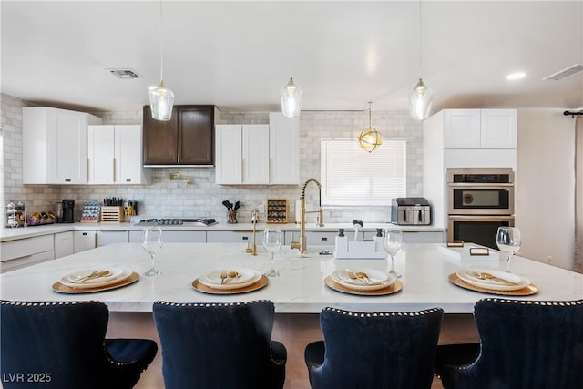 4774 Walteta Way, Las Vegas, NV 89119 - kitchen featuring appliances with stainless steel finishes, decorative backsplash, decorative light fixtures, and a breakfast bar