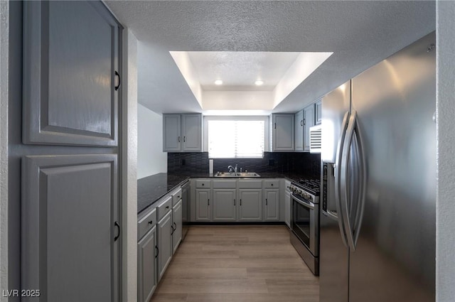 9449 Amber Valley Ln, Las Vegas, NV 89134 - kitchen featuring appliances with stainless steel finishes, a tray ceiling, light wood-style flooring, decorative backsplash, and recessed lighting