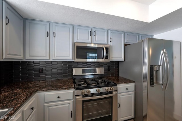 9449 Amber Valley Ln, Las Vegas, NV 89134 - kitchen with stainless steel appliances, tasteful backsplash, dark stone countertops, and white cabinets