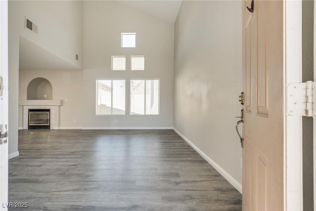7816 Calico Flower Ave, Las Vegas, NV 89128 - unfurnished living room featuring wood finished floors, a tiled fireplace, and lofted ceiling