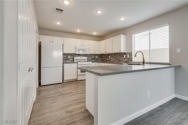 7816 Calico Flower Ave, Las Vegas, NV 89128 - kitchen with white appliances, light wood-type flooring, tasteful backsplash, a peninsula, and white cabinets