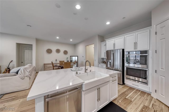 32 Tatahatso Point St, Henderson, NV 89011 - kitchen featuring appliances with stainless steel finishes, open floor plan, white cabinetry, light wood finished floors, and a kitchen island with sink