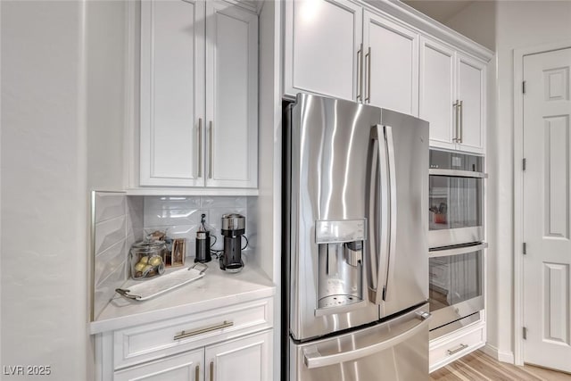 32 Tatahatso Point St, Henderson, NV 89011 - kitchen featuring stainless steel appliances, light countertops, white cabinets, tasteful backsplash, and light wood finished floors