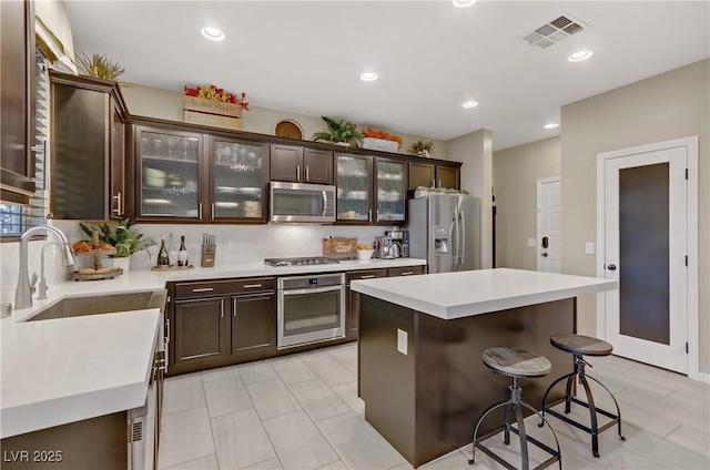 8992 Sparkling River Ct, Las Vegas, NV 89178 - kitchen featuring stainless steel appliances, dark brown cabinets, light countertops, a kitchen bar, and recessed lighting