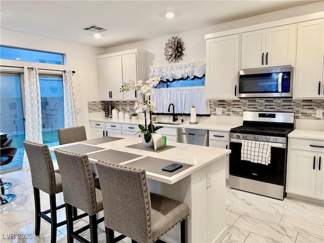 10411 Rose Palisade St, Las Vegas, NV 89141 - kitchen featuring appliances with stainless steel finishes, light marble finish flooring, a kitchen breakfast bar, tasteful backsplash, and light countertops