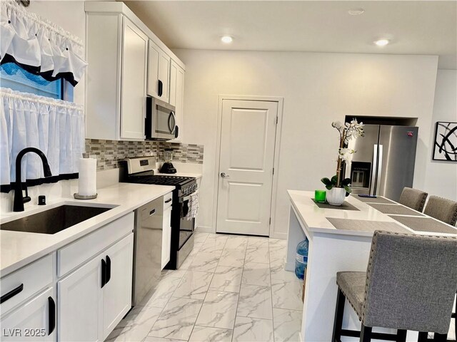 10411 Rose Palisade St, Las Vegas, NV 89141 - kitchen with appliances with stainless steel finishes, a kitchen breakfast bar, light marble finish floors, white cabinets, and recessed lighting