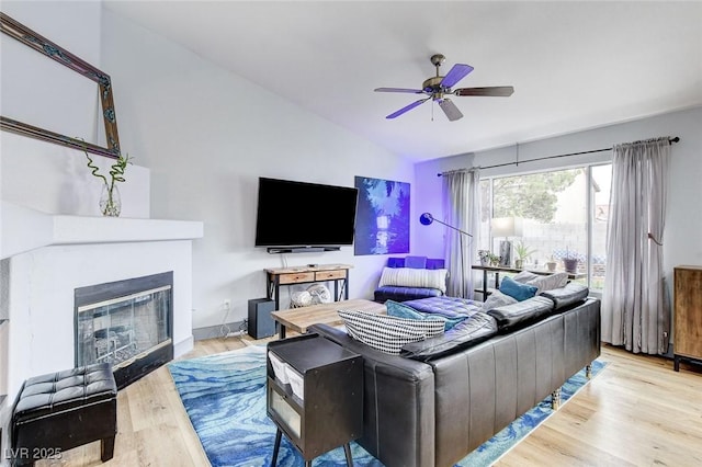 8926 Termoli St, Las Vegas, NV 89123 - living room featuring vaulted ceiling, ceiling fan, wood finished floors, and a glass covered fireplace
