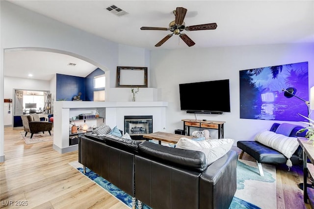 8926 Termoli St, Las Vegas, NV 89123 - living room featuring arched walkways, light wood finished floors, ceiling fan, a glass covered fireplace, and lofted ceiling