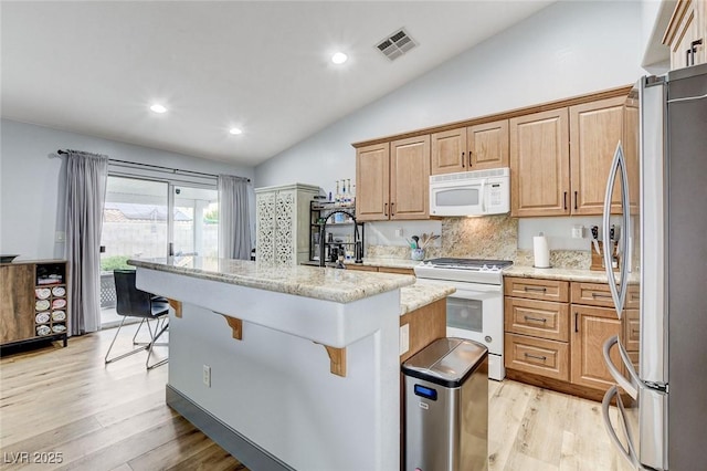 8926 Termoli St, Las Vegas, NV 89123 - kitchen featuring white appliances, lofted ceiling, a breakfast bar area, light wood-type flooring, and a center island with sink