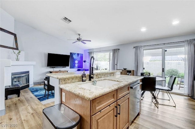 8926 Termoli St, Las Vegas, NV 89123 - kitchen with dishwasher, light wood-type flooring, a glass covered fireplace, light stone countertops, and ceiling fan