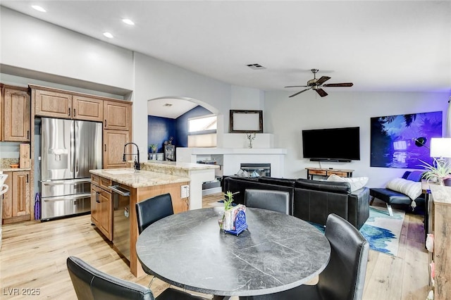 8926 Termoli St, Las Vegas, NV 89123 - dining space featuring vaulted ceiling, light wood-style floors, ceiling fan, a glass covered fireplace, and arched walkways