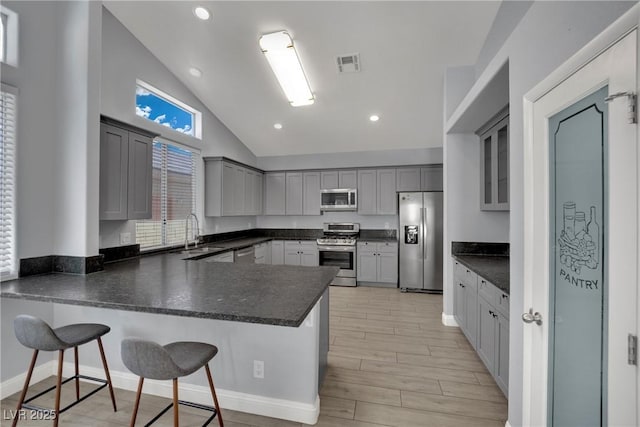 5509 Rose Thicket St, Las Vegas, NV 89130 - kitchen with appliances with stainless steel finishes, a peninsula, dark countertops, light wood-type flooring, and high vaulted ceiling