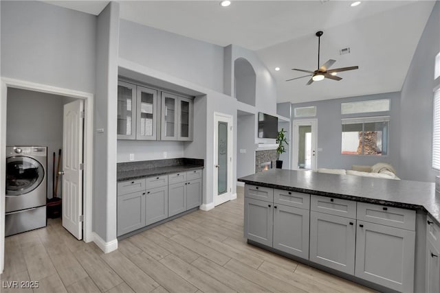 5509 Rose Thicket St, Las Vegas, NV 89130 - kitchen with washer / dryer, ceiling fan, gray cabinets, glass insert cabinets, and high vaulted ceiling