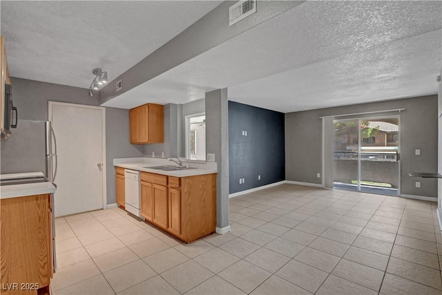 201 Mission Laguna Ln Unit 104, Las Vegas, NV 89107 - kitchen with white dishwasher, freestanding refrigerator, light countertops, a textured ceiling, and light tile patterned floors