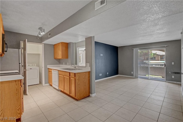 201 Mission Laguna Ln Unit 104, Las Vegas, NV 89107 - kitchen with washer / clothes dryer, white dishwasher, light countertops, light tile patterned flooring, and a textured ceiling
