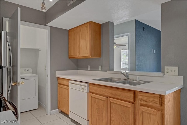 201 Mission Laguna Ln Unit 104, Las Vegas, NV 89107 - kitchen featuring white dishwasher, washer / dryer, light tile patterned floors, freestanding refrigerator, and light countertops