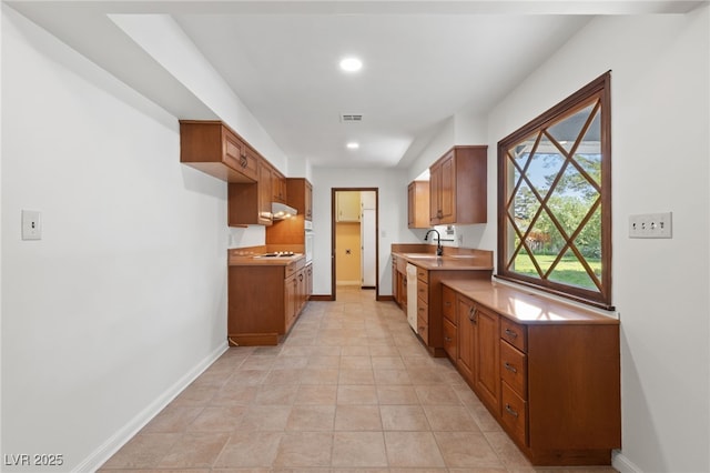 2400 Llewellyn Dr, Las Vegas, NV 89102 - kitchen featuring under cabinet range hood, stovetop, brown cabinets, light countertops, and recessed lighting