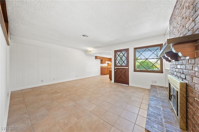 2400 Llewellyn Dr, Las Vegas, NV 89102 - unfurnished living room featuring a brick fireplace, a textured ceiling, and light tile patterned floors