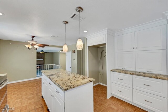 3746 E Harmon Ave, Las Vegas, NV 89121 - kitchen featuring ceiling fan, white cabinets, hanging light fixtures, light stone countertops, and a center island