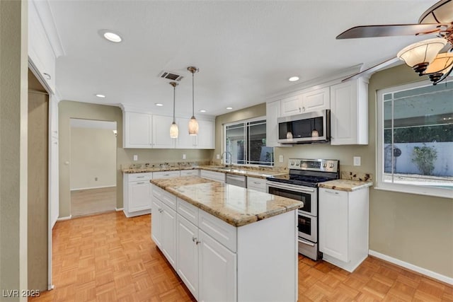 3746 E Harmon Ave, Las Vegas, NV 89121 - kitchen with appliances with stainless steel finishes, a center island, white cabinets, hanging light fixtures, and recessed lighting