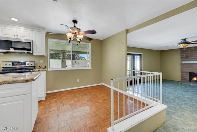 3746 E Harmon Ave, Las Vegas, NV 89121 - kitchen featuring stainless steel appliances, ceiling fan, light stone countertops, and white cabinetry