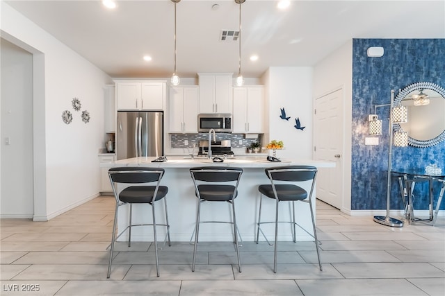 3782 Neblina Dr, Henderson, NV 89052 - kitchen with appliances with stainless steel finishes, a kitchen island with sink, backsplash, a breakfast bar, and recessed lighting