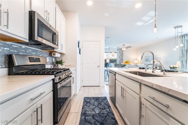 3782 Neblina Dr, Henderson, NV 89052 - kitchen featuring stainless steel appliances, tasteful backsplash, open floor plan, white cabinets, and light stone counters