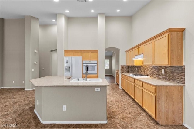 9233 Onyx Point Ct, Henderson, NV 89074 - kitchen with white appliances, a towering ceiling, arched walkways, light countertops, and a kitchen island with sink
