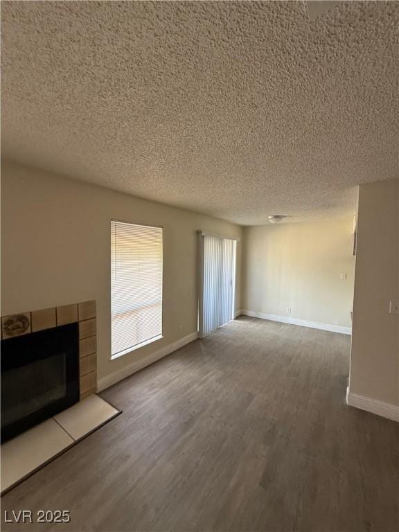 4941 Newport Cove Dr Unit B, Las Vegas, NV 89119 - unfurnished living room with a textured ceiling, wood finished floors, and a tiled fireplace