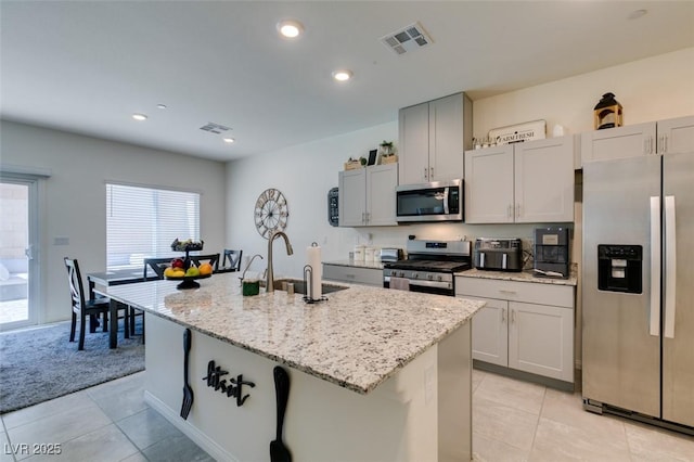 10939 Cheshire Woods Ave, Las Vegas, NV 89166 - kitchen featuring appliances with stainless steel finishes, light tile patterned floors, an island with sink, light stone countertops, and recessed lighting