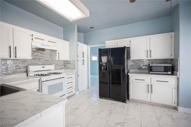 6524 Rain Forest Dr, Las Vegas, NV 89108 - kitchen featuring black fridge, white range with gas cooktop, stainless steel microwave, light marble finish floors, and under cabinet range hood