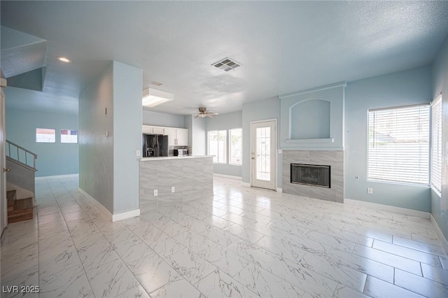 6524 Rain Forest Dr, Las Vegas, NV 89108 - unfurnished living room featuring a tile fireplace, plenty of natural light, light marble finish floors, a ceiling fan, and recessed lighting